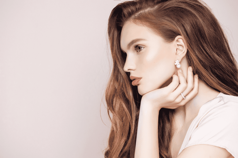 mujer con anillo fino y pendientes de perlas