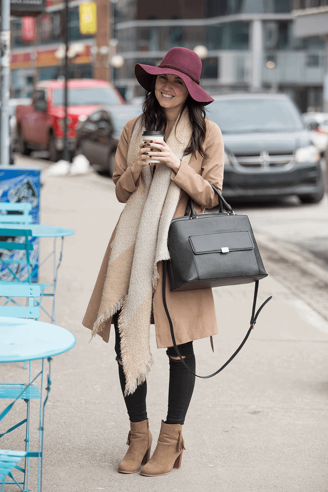 mujer con un bolso negro de piel y bufanda en colores neutros